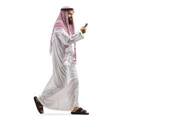 Full length profile shot of an arab man using a smartphone and walking