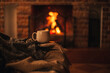 © polinaloves - Mug with hot tea standing on a chair with woolen blanket in a cozy living room with fireplace.