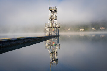 Wall Mural - Clairvaux-Les-Lacs, France - 09 02 2020: Fog and reflections on the big lake - La Raillette