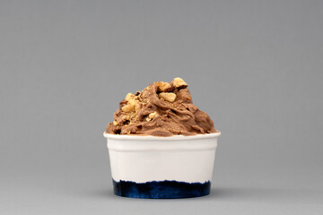 Hazelnut ice cream in cup on gray background