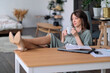 Happy businesswoman sitting with her feet up in her office. Young woman working from home office. Freelancer using laptop and the Internet. Workplace in living room.