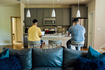 Wall Mural - gay couple working from home on laptop computers sitting at kitchen counter