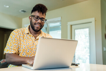 Wall Mural - smiling man working from home on laptop computer