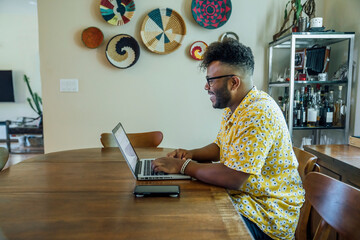 Wall Mural - man working from home on laptop computer sitting at dining room table