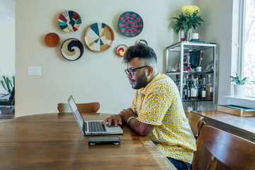 Wall Mural - man working from home on laptop computer sitting at dining room table