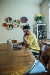 Wall Mural - man working from home on laptop computer sitting at dining room table