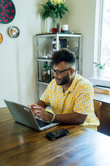 Wall Mural - man working from home on laptop computer sitting at dining room table