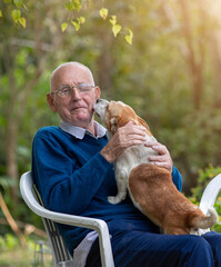 Dog kissing old man in garden