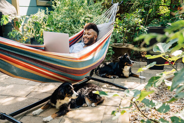 Wall Mural - man relaxing in hammock working on laptop computer