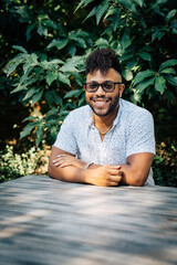 Wall Mural - Portrait of happy black man with sitting in yard at table