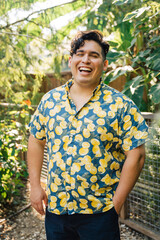 Wall Mural - Portrait of happy, smiling latinx man in bright patterned shirt standing outside in garden