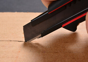 man cuts cardboard with a construction knife, construction and repair concept, do it yourself.