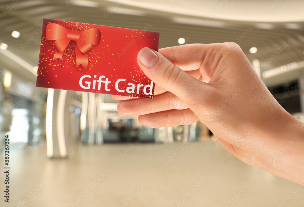Woman holding gift card in shopping mall, closeup - obrazy, fototapety, plakaty 