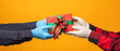 © Chanakon - Close up hands wearing medical rubber glove giving the present gift box in christmas day on yellow background. Merry christmas and happy new years and sending the gift.