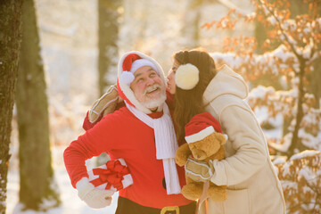 Santa Claus kisses a woman. Christmas and New year. Santa Claus with girl kissing outdoor in snow.