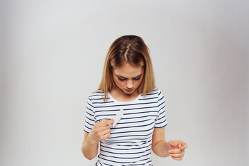 Wall Mural - Woman with a business card in her hands a striped T-shirt advertising light background