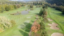 Aerial View Of Golf Course With A Rich Green Turf, Putting Green, Sand Bunker And Water Hazards.