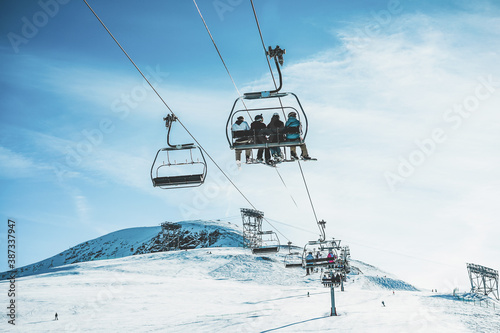 Fotografía People on ski lift in winter ski resort - Focus on guys sitting in cable car