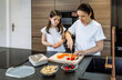 © David Pereiras - Mother preparing healthy snack for her daughter for school while she watches her