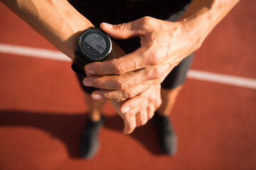 Sportsman looking at watch on track