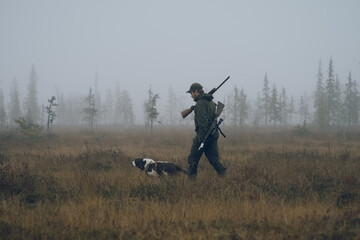 hunter crossing foggy swamp with his dog