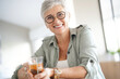 © goodluz - Cheerful 50-year woman drinking hot tea at home