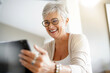 © goodluz - Cheerful mature woman with eyeglasses using digital tablet