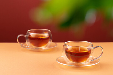 Two glass cups of black tea on beige table