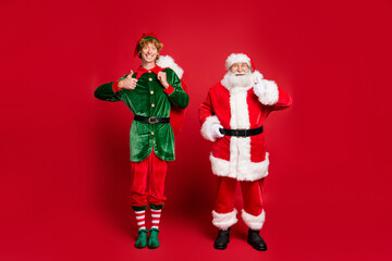 Canvas Print - Full length photo of two people santa elf hold big bag raise thumb up wear x-mas costume cap glasses boots isolated red color background