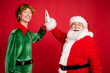 © deagreez - Profile photo of two men santa claus elf clap palms give five wear x-mas costume coat headwear isolated red color background