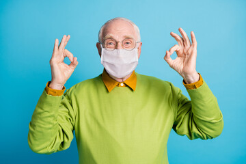 Photo of pensioner raise two arms showing okey wear white face mask isolated blue color background