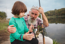 Adorable Little Boy Learning About Fishing From His Grandfather, Enjoying Day On The Lake Together