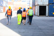 © NVB Stocker - Group of professional team worker walking to working and wearing protection face mask during coronavirus and flu outbreak and wearing safety hardhat helmet at container yard or cargo warehouse