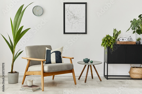 Modern retro concept of home interior with design grey armchair, coffee table, plants, mock up poster map, carpet and personal accessoreis. Stylish home decor of living room.