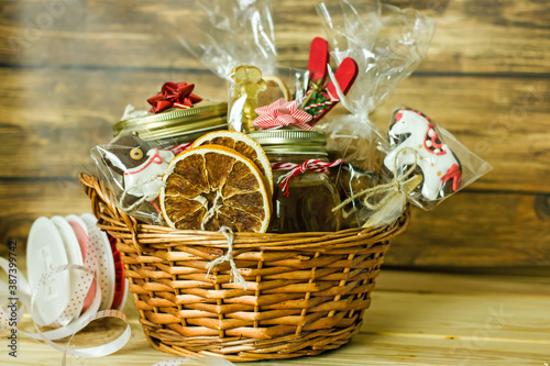 Christmas food gift basket. Edible Christmas gift made of cookies, honey, homemade handmade sweets, dried oranges, lollipops on a wooden table.Concept handmade christmas gifts, Handmade food presents