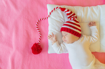 Poster - Baby sleeps in a Santa hat. Selective focus.