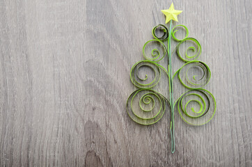 Wall Mural - A green quilling paper origami chirstmas tree with star on wooden background