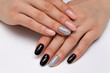 © dina_shuba - Black, beige, silver, shiny manicure with crystals on short oval nails close-up on a white background.