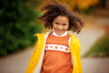 Wall Mural - Cute afro girl smiling broadly outdoors and enjoying autumn day in park.