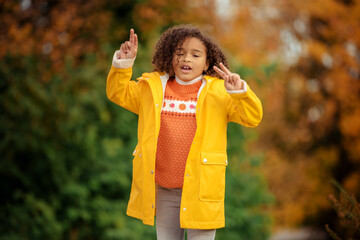 Wall Mural - Cute afro girl smiling broadly outdoors and enjoying autumn day in park.