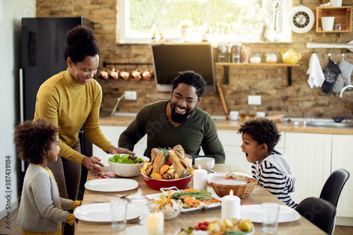 Happy African American family enjoying in Thanksgiving lunch in dining room.