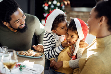 Wall Mural - Loving African American boy kissing his sister on Christmas day.