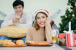 © chinnarach - close up young asian woman sitting on dining table with man sit on sofa in living room with decorative Christmas pine tree for celebration party at home concept