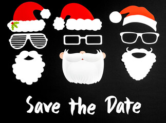 English Text Save The Date. Three Santa Claus Paper Mask With Christmas Decoration And Accessories Like Hat, Glasses And Bear. Black Paper Background
