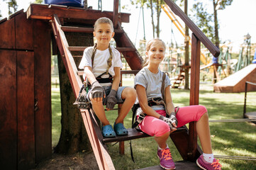 Wall Mural - Little girl and boy sitting on stairs in rope park