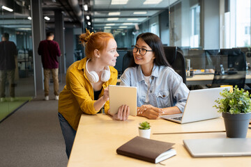 Poster - Two young intercultural female managers looking at one another with smiles