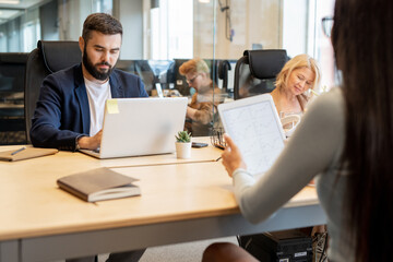 Canvas Print - Young bearded businessman and mature blond female working individually