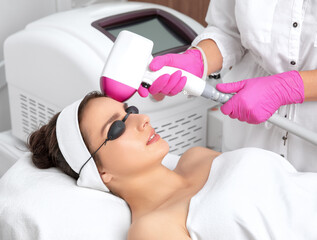 Elos epilation hair removal procedure on the face of a woman. Beautician doing laser rejuvenation on the forehead in a beauty salon. Facial skin care. Hardware ipl cosmetology