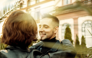 Wall Mural - Young couple in love hugs and spend time together in the city against the backdrop of urban architecture.