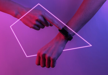 Wall Mural - Female hand with a smart bracelet. Modern gadgets. Creative pop art pink blue neon color. Trendy gradient illumination. Night light